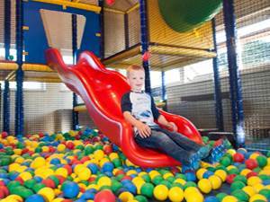Foto 2: Kind glijdt van de glijbaan in de ballenbak van indoorspeelplaats van Landal Orveltermarke