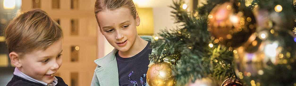 Kinderen versieren en kijken naar kerstboom in vakantiehuis van Hof van Saksen