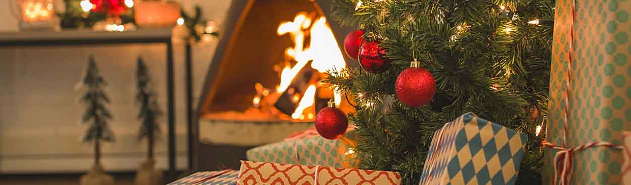 Open haard en kerstboom met versieringen en pakjes bij de open haard in een vakantiehuisje van Landal GreenParks